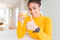 Young african american woman drinking a glass of fresh orange juice happy with big smile doing ok sign, thumb up with fingers, Royalty Free Stock Photo