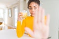 Young african american woman drinking a glass of fresh orange juice with open hand doing stop sign with serious and confident Royalty Free Stock Photo