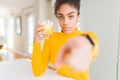 Young african american woman drinking a glass of fresh orange juice pointing with finger to the camera and to you, hand sign, Royalty Free Stock Photo