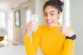 Young african american woman drinking a glass of fresh water very happy pointing with hand and finger Royalty Free Stock Photo