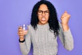 Young african american woman drinking glass of water over isolated purple background annoyed and frustrated shouting with anger,