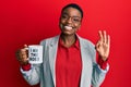 Young african american woman drinking from i am the boss coffee cup doing ok sign with fingers, smiling friendly gesturing Royalty Free Stock Photo