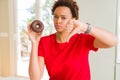 Young african american woman eating chocolate donut with angry face, negative sign showing dislike with thumbs down, rejection