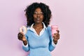 Young african american woman eating doughnut and drinking coffee looking at the camera blowing a kiss being lovely and sexy Royalty Free Stock Photo