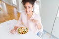 Young african american woman eating healthy pasta salad with surprise face pointing finger to himself Royalty Free Stock Photo