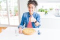 Young african american woman eating homemade cheese pizza happy with big smile doing ok sign, thumb up with fingers, excellent Royalty Free Stock Photo