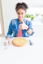 Young african american woman eating homemade cheese pizza happy with big smile doing ok sign, thumb up with fingers, excellent Royalty Free Stock Photo