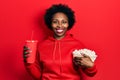 Young african american woman eating popcorn and drinking soda smiling with a happy and cool smile on face Royalty Free Stock Photo