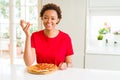 Young african american woman eating tasty peperoni pizza with a happy face standing and smiling with a confident smile showing Royalty Free Stock Photo