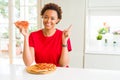 Young african american woman eating tasty peperoni pizza very happy pointing with hand and finger to the side Royalty Free Stock Photo