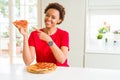 Young african american woman eating tasty peperoni pizza very happy pointing with hand and finger Royalty Free Stock Photo