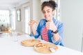 Young african american woman eating two homemade cheese pizzas happy with big smile doing ok sign, thumb up with fingers, Royalty Free Stock Photo