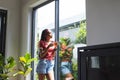 A young African American woman enjoys a slice of pizza by a sunny window Royalty Free Stock Photo