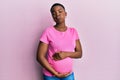 Young african american woman expecting a baby, touching pregnant belly puffing cheeks with funny face Royalty Free Stock Photo