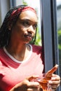 A young African American woman gazes out a window, holding a cup of tea Royalty Free Stock Photo
