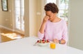 Young african american woman having healthy breakfast in the morning at home tired rubbing nose and eyes feeling fatigue and Royalty Free Stock Photo