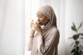 Young African American woman in hijab having lazy morning with aromatic coffee at home, drinking hot beverage indoors Royalty Free Stock Photo