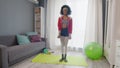 Young african american woman hippy in colourful sportswear with curly afro hairs looks ant the camera and lifts