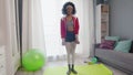 Young african american woman hippy in colourful sportswear with curly afro hairs looks ant the camera and lifts