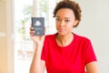 Young african american woman holding Australian passport with a confident expression on smart face thinking serious