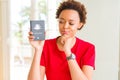 Young african american woman holding Australian passport serious face thinking about question, very confused idea