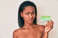 Young african american woman holding birth control pills clueless and confused expression Royalty Free Stock Photo