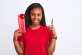 Young african american woman holding birthday present over isolated background surprised with an idea or question pointing finger Royalty Free Stock Photo