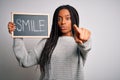 Young african american woman holding blackboard with smile word text over isolated background pointing with finger to the camera Royalty Free Stock Photo