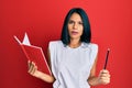 Young african american woman holding book and pencil skeptic and nervous, frowning upset because of problem Royalty Free Stock Photo