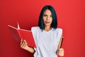 Young african american woman holding book and pencil skeptic and nervous, frowning upset because of problem Royalty Free Stock Photo