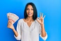 Young african american woman holding 10 colombian pesos banknotes smiling positive doing ok sign with hand and fingers Royalty Free Stock Photo