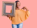 Young african american woman holding empty frame pointing finger to one self smiling happy and proud Royalty Free Stock Photo