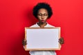 Young african american woman holding empty white chalkboard making fish face with mouth and squinting eyes, crazy and comical Royalty Free Stock Photo