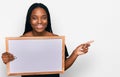 Young african american woman holding empty white chalkboard smiling happy pointing with hand and finger to the side Royalty Free Stock Photo