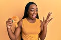 Young african american woman holding fourth place badge celebrating victory with happy smile and winner expression with raised Royalty Free Stock Photo