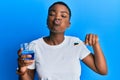 Young african american woman holding glass of mouthwash and toothbrush for fresh breath puffing cheeks with funny face Royalty Free Stock Photo