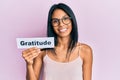 Young african american woman holding gratitude message paper looking positive and happy standing and smiling with a confident