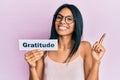 Young african american woman holding gratitude message paper smiling happy pointing with hand and finger to the side