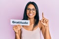 Young african american woman holding gratitude message paper smiling with an idea or question pointing finger with happy face,