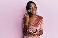 Young african american woman holding makeup brush and blush palette smiling looking to the side and staring away thinking