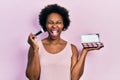 Young african american woman holding makeup brush and blush sticking tongue out happy with funny expression