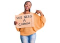 Young african american woman holding we need a change banner pointing finger to one self smiling happy and proud