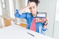 Young african american woman holding shadows cosmetics palette stressed with hand on head, shocked with shame and surprise face, Royalty Free Stock Photo