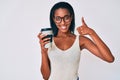 Young african american woman holding take away coffee smiling happy and positive, thumb up doing excellent and approval sign Royalty Free Stock Photo