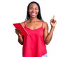 Young african american woman holding touchpad surprised with an idea or question pointing finger with happy face, number one