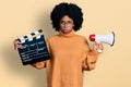 Young african american woman holding video film clapboard and megaphone depressed and worry for distress, crying angry and afraid