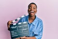 Young african american woman holding video film clapboard smiling and laughing hard out loud because funny crazy joke Royalty Free Stock Photo