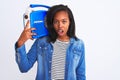 Young african american woman holding vintage retro radio over isolated background scared in shock with a surprise face, afraid and Royalty Free Stock Photo