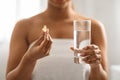 African American Woman Holding Vitamin Capsule And Glass Of Water At Home Royalty Free Stock Photo