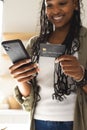 A young African American woman holds a smartphone and a credit card Royalty Free Stock Photo